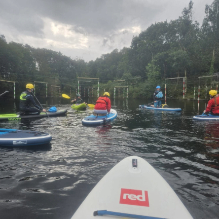 Two men in traditional attire practicing martial arts on a sandy beach.